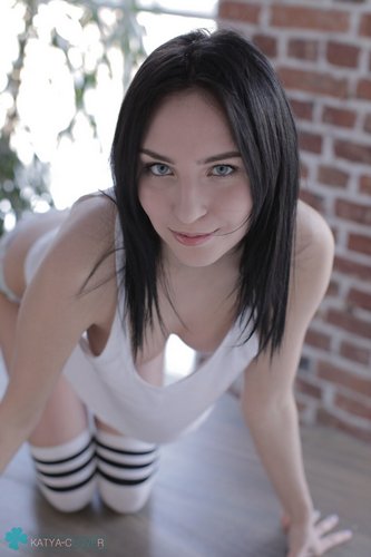 Брюнетка в чулках и майке позирует на столе